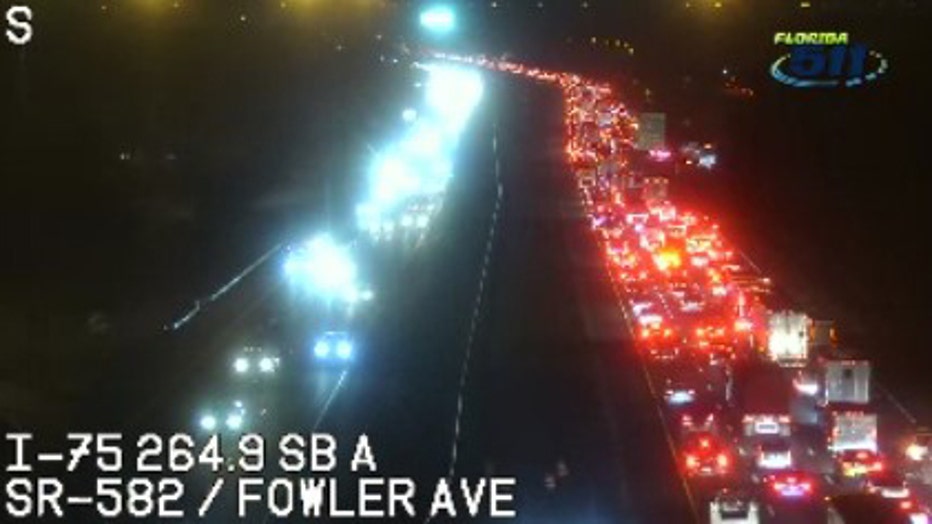 Traffic camera view of I-75 Southbound near Fowler Avenue in Tampa at night, showing heavy congestion in the right lanes with long lines of red brake lights.